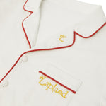 Close-up of a Big Folk pyjama top with red piping trim and yellow embroidered text reading 'Lapland' on the chest pocket.