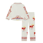 A two-piece Small Folk pajama set featuring a long-sleeve top and matching pants in an off-white fabric. The set is decorated with colorful Christmas-themed prints, including red moose, a festive border, and small blue text labels.